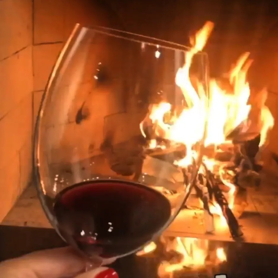 Taça de vinho em frente à lareira acesa